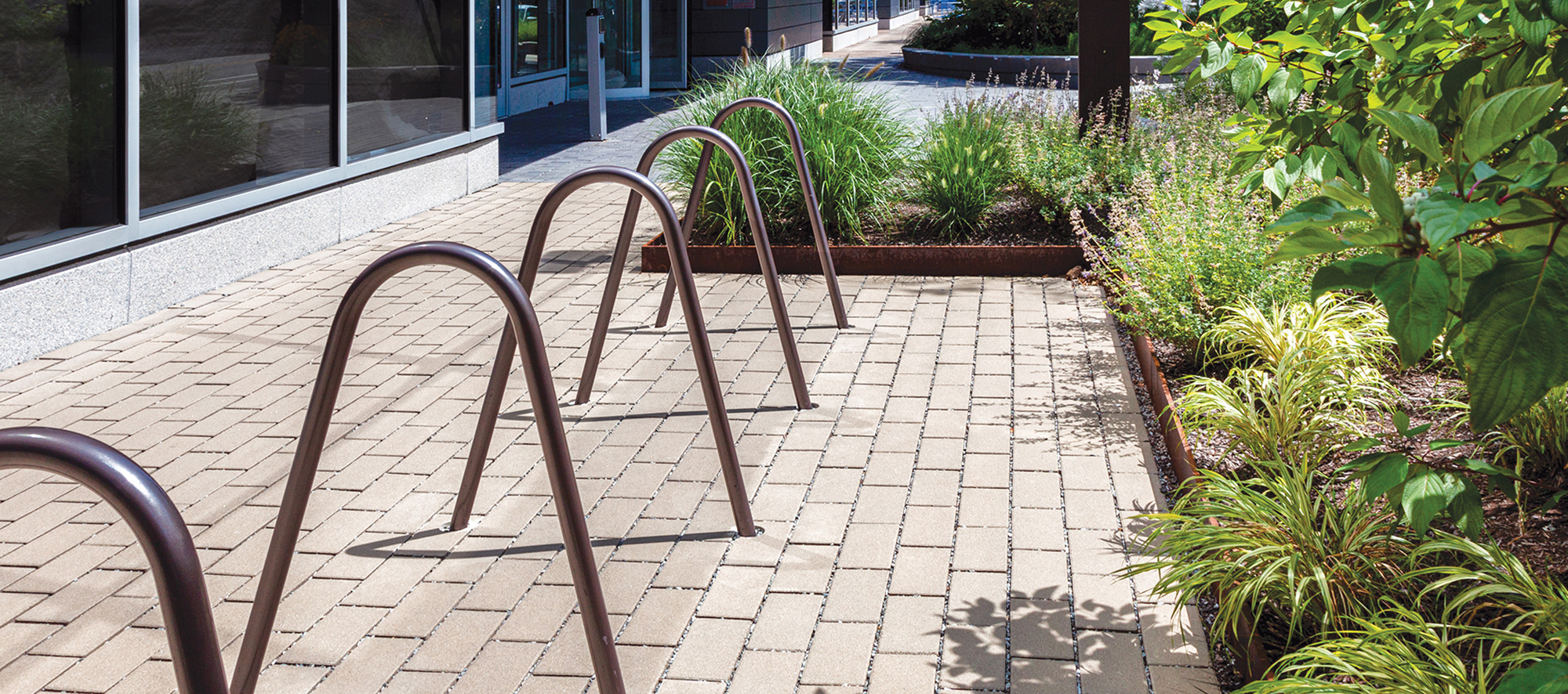 Unilock Eco-Priora permeable pavers in front of a building with bike racks and gardens.
