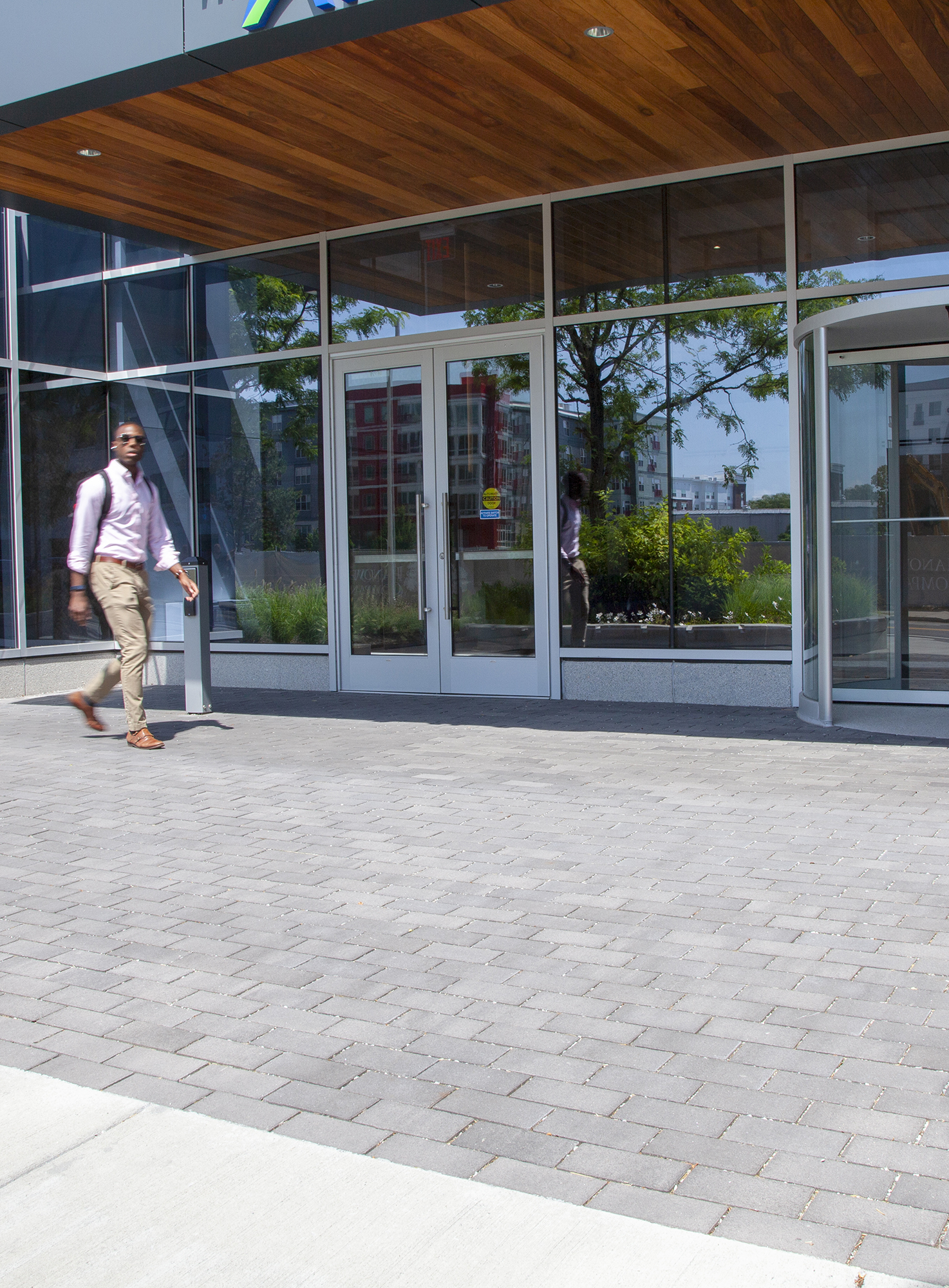 A man walks in front of the entrance of a building, on an area paved with Unilock Eco-Priora permeable pavers.