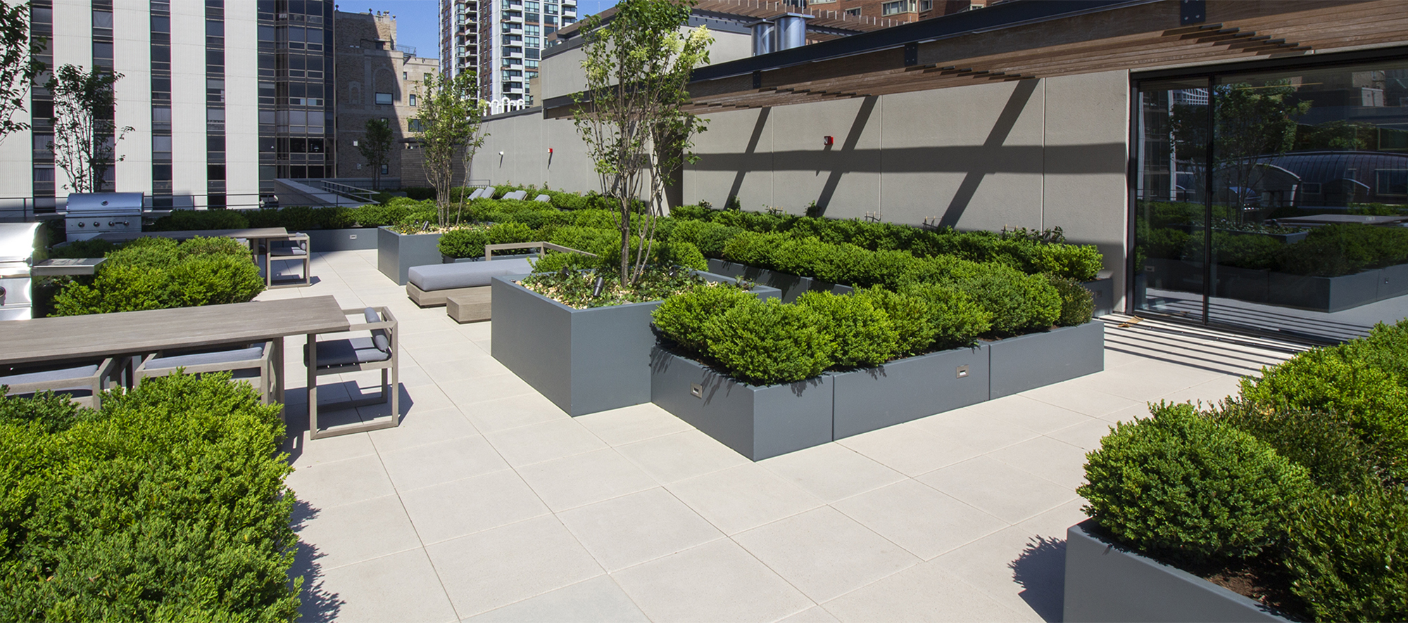 Seating areas and raised gardens sit atop Unilock Arcana slabs in a light color on the roof deck of 61 E banks roof in Chicago.