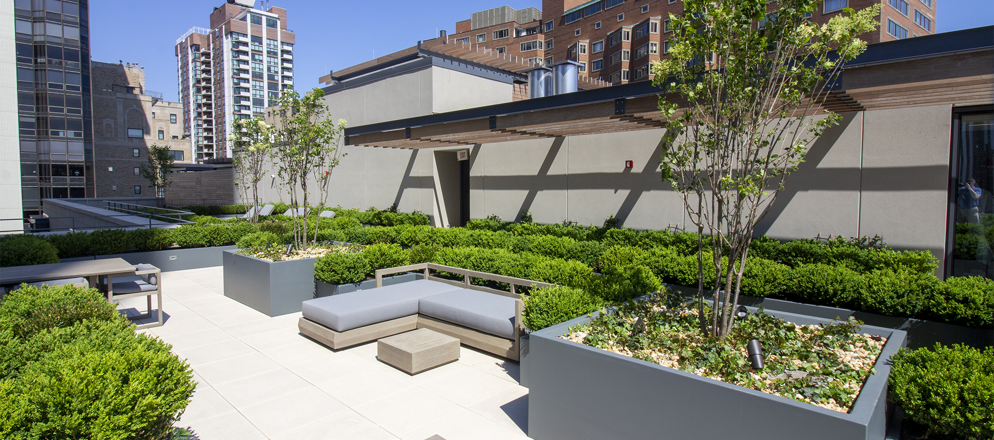 Seating areas and raised gardens sit atop Unilock Arcana slabs in a light color on the roof deck of 61 E banks roof in Chicago.