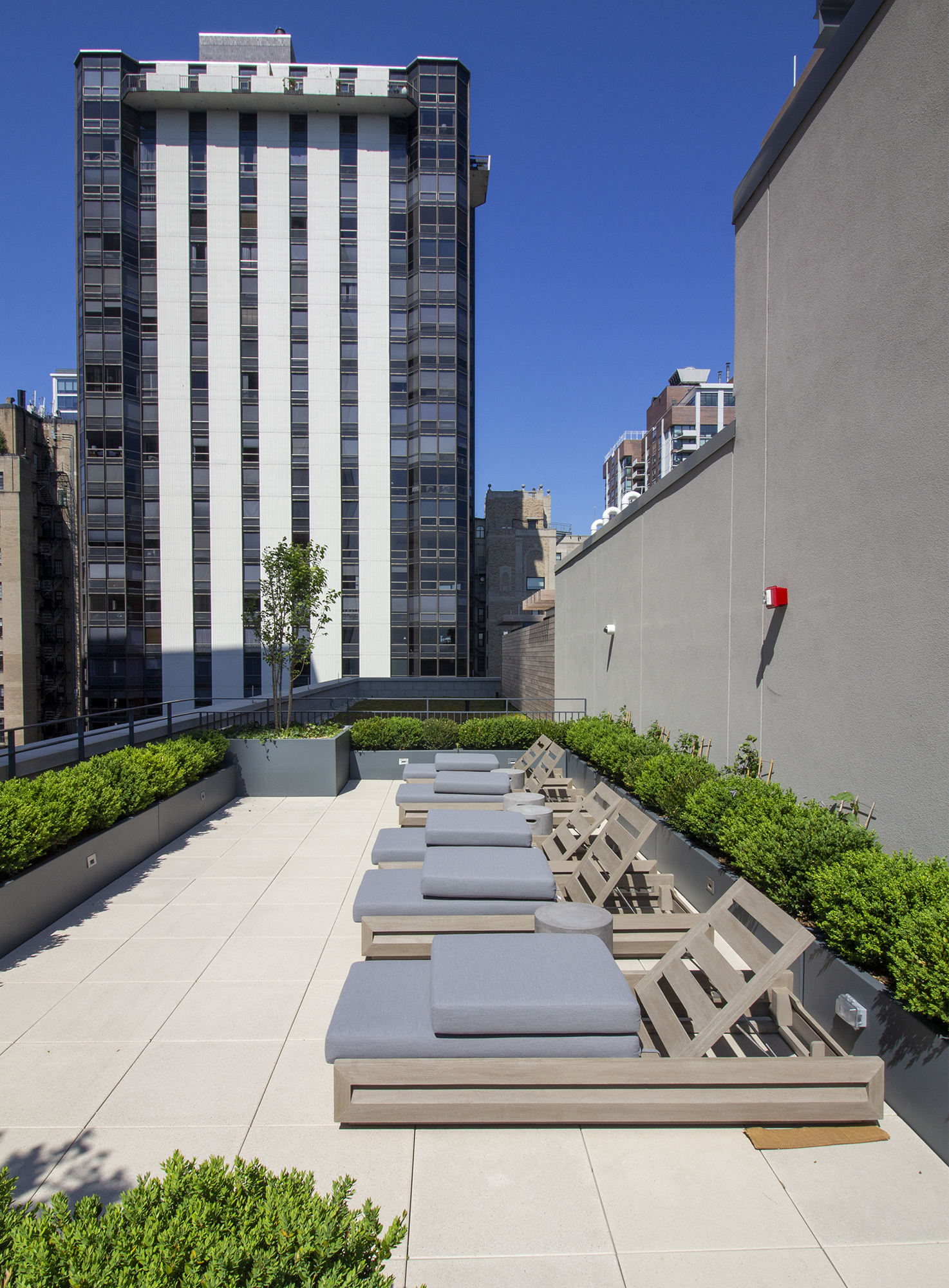 Seating areas and raised gardens on a roof deck made of Unilock Arcana slabs are backed by a wall, and look out onto the Chicago skyline.