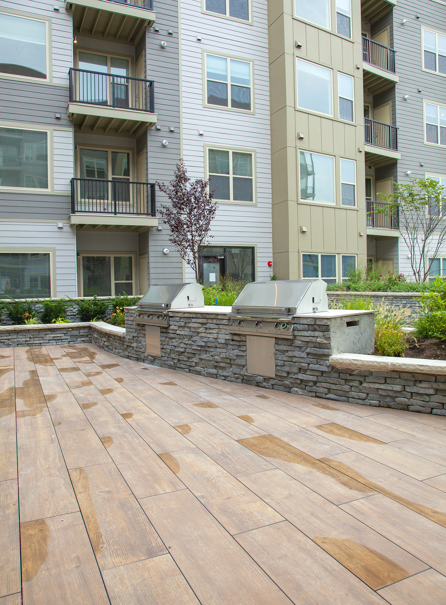 The top floors of Avalon Yonkers condominiums overlook a roof deck with Rivercrest wall garden beds and grilling stations on wooden planks.