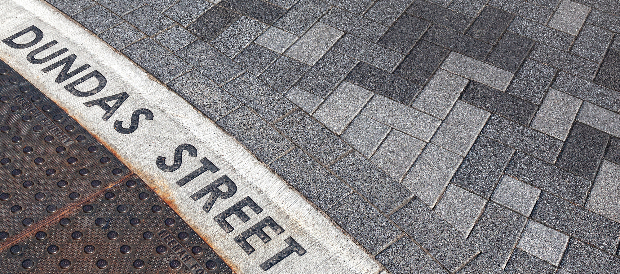 The Words "Dundas Street" are laid into a curb below Series pavers in alternating patterns and colors.