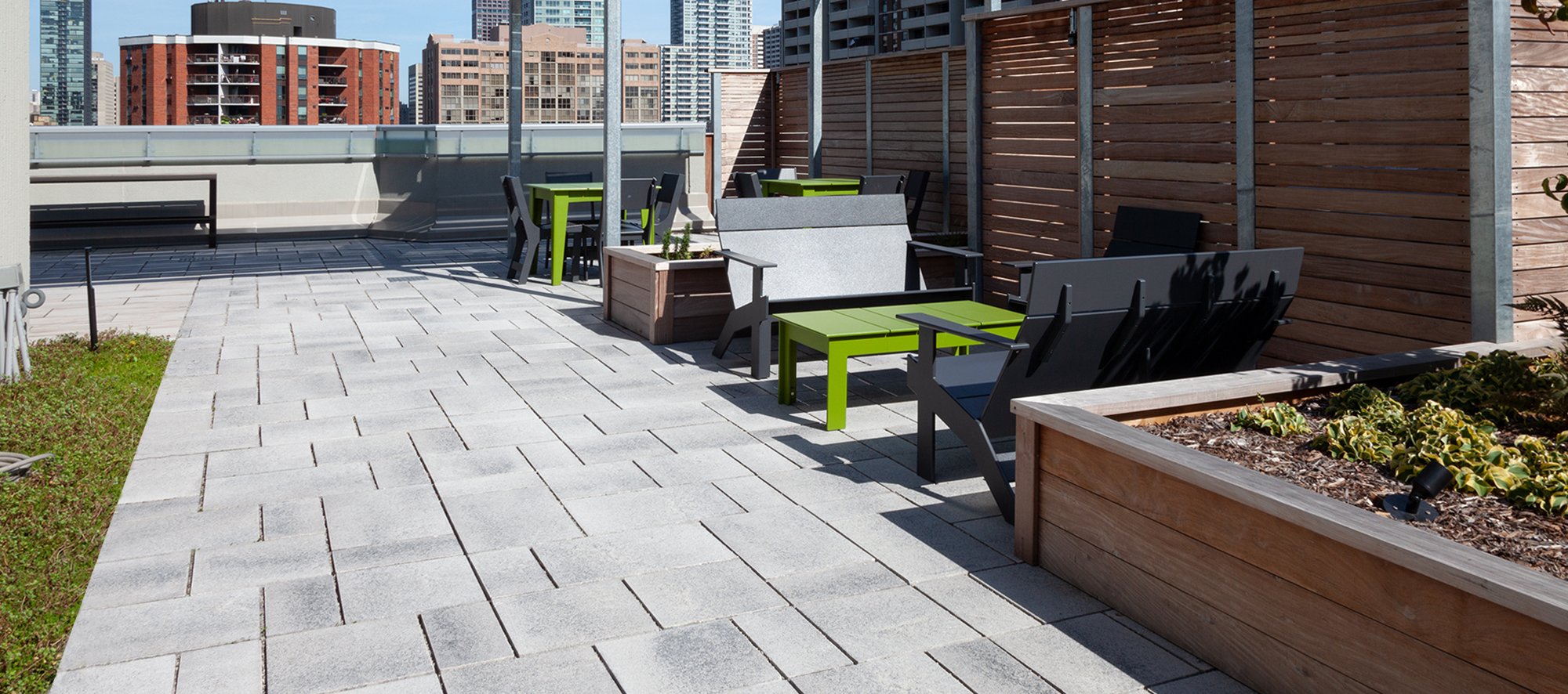 The roof deck at 130 Carlton, Toronto features Umbriano slabs in Winter Marvel by Unilock and a view of the Toronto skyline.