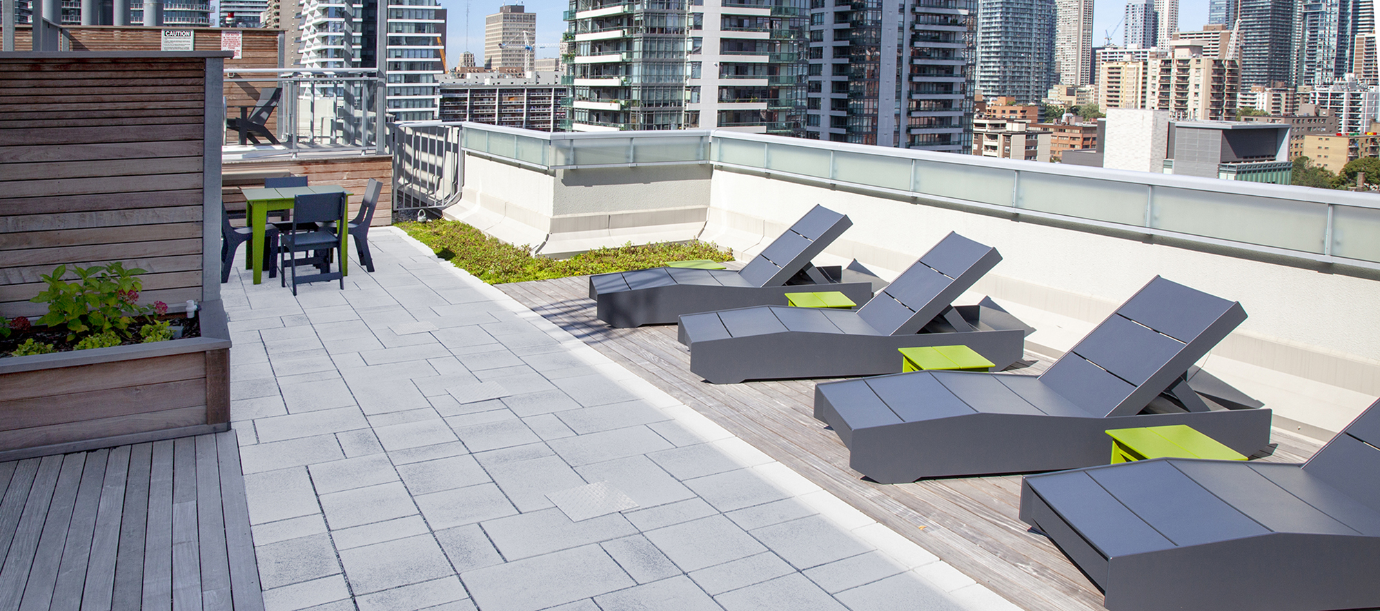 The roof deck at 130 Carlton, Toronto features grey speckled, Umbriano Winter Marvel pavers by Unilock and a view of the Toronto skyline.