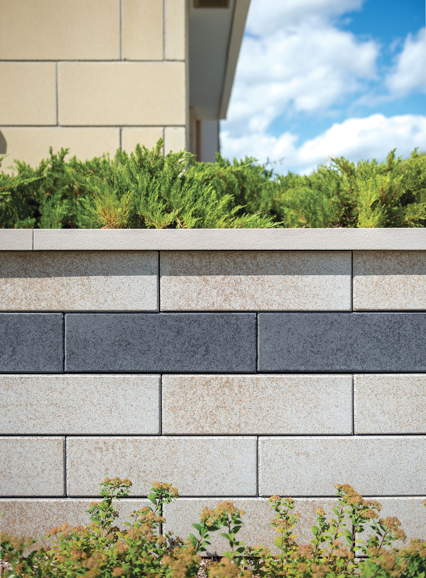 This U-Cara retaining wall uses light brown and black colors to draw attention to the green patches throughout this space.