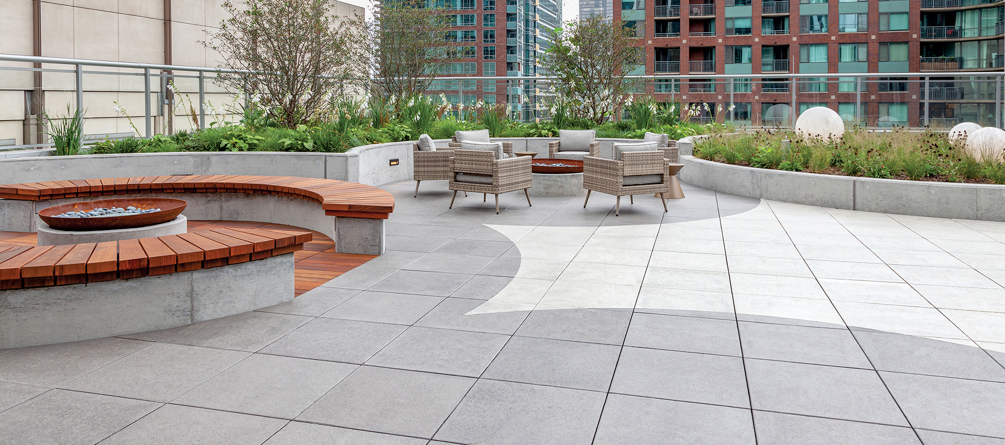 A circular themed roof deck created with Unilock Arcana slabs in white and grey offers condo residents firepits, seating, and gardens.
