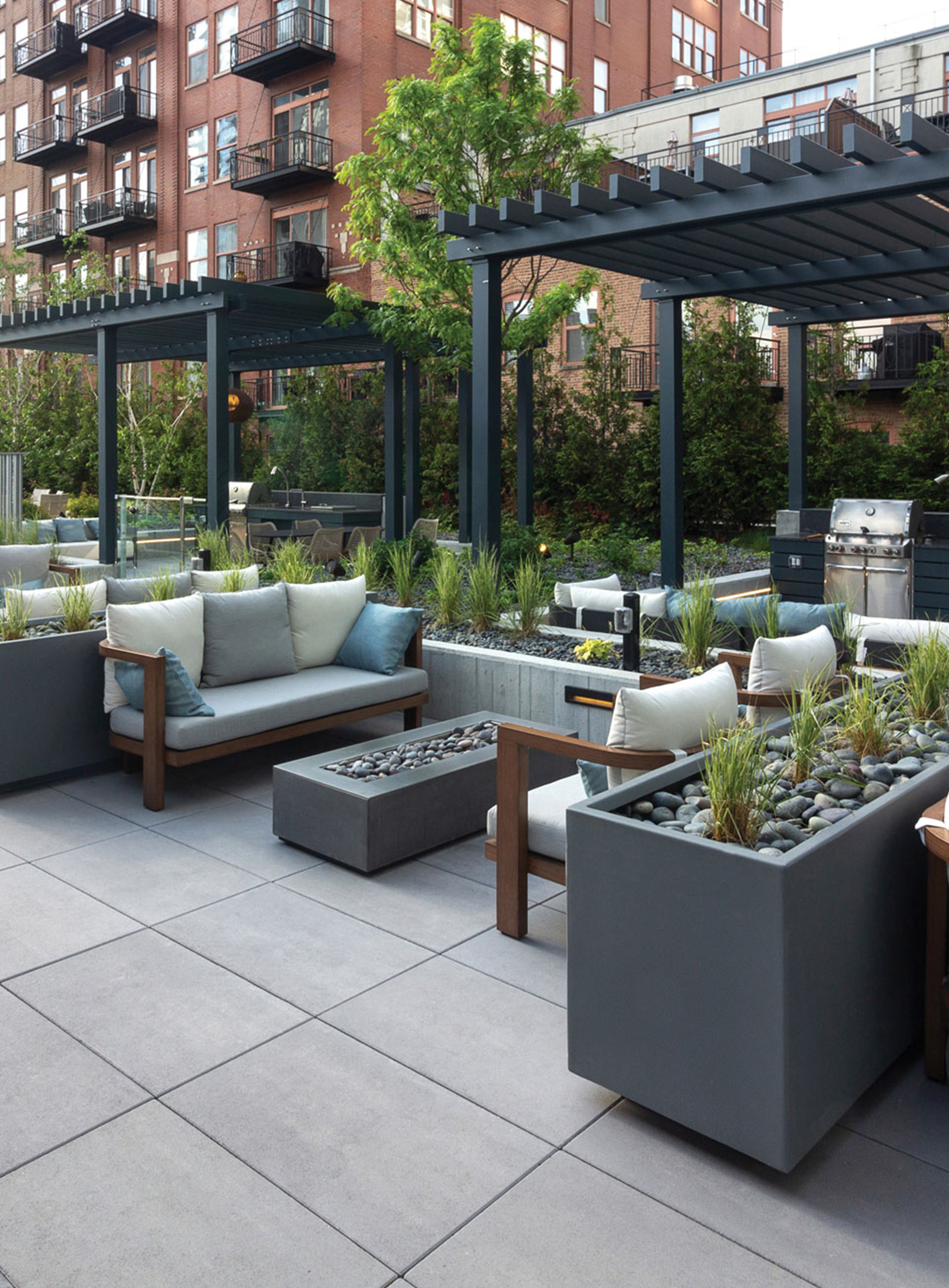 A Chicago roof deck amenity space paved with Unilock Beacon Hill Smooth XL features conversation areas, plant boxes, and outdoor kitchens.