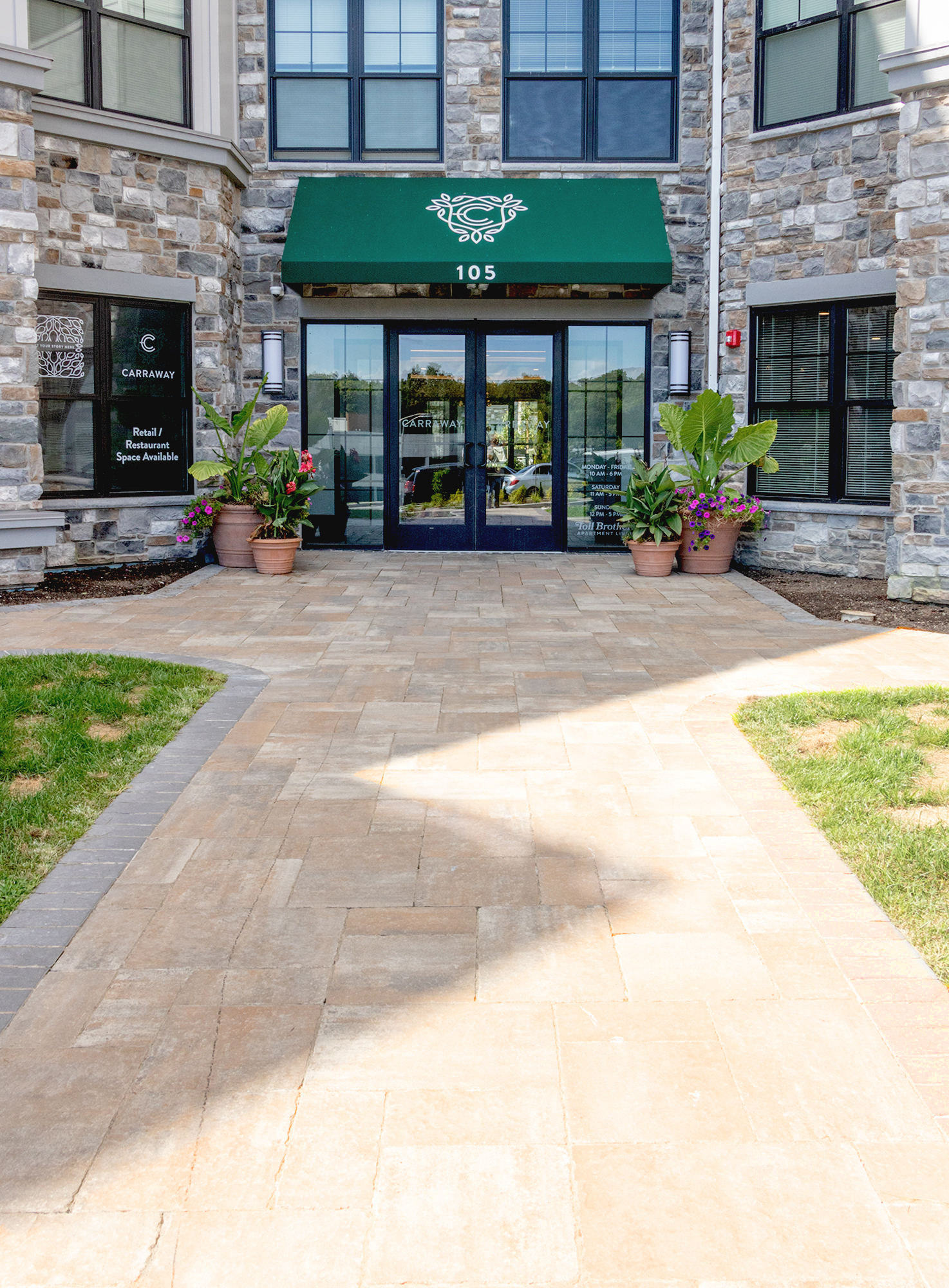 Brown-colored Bristol Valley pavers guide visitors the entryway of the brick condo building, with decorative seasonal planters at the door.