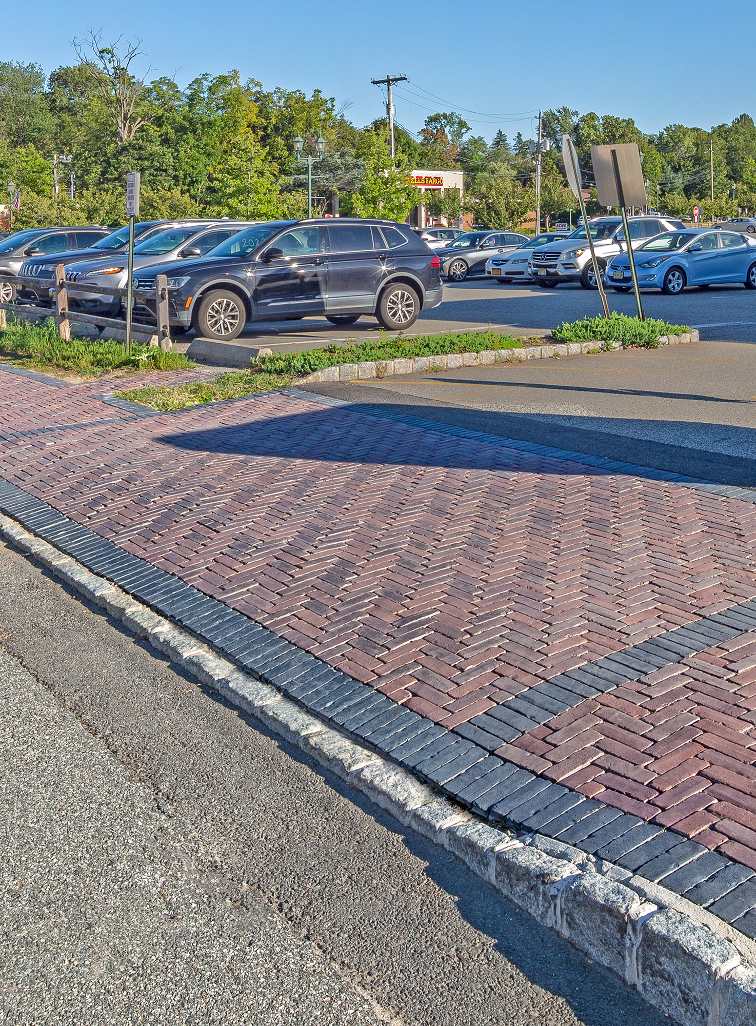 A historic street with large sidewalks paved in warm red tones of Unilock Copthorne in a herringbone pattern with a contrasting border.