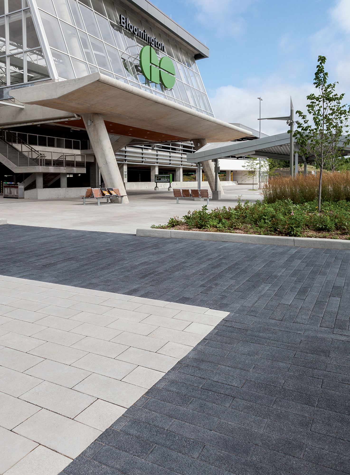 A Bloomington Go entrance has benches, signs and wastebins on white Umbriano pavers with walking areas delineated by Black Series pavers.