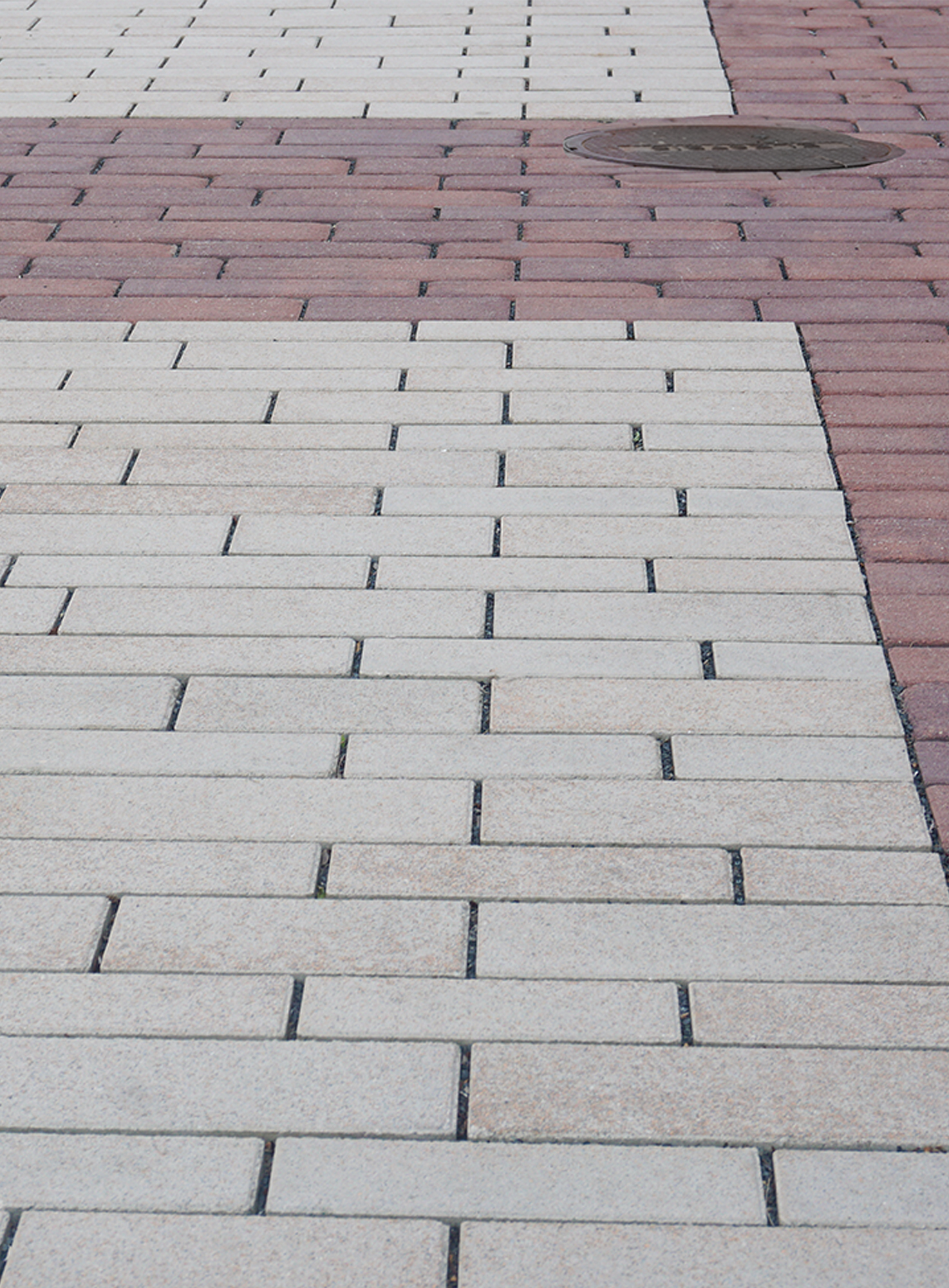 Red and beige Eco-Line pavers are placed in a running bond pattern to create distinct, patterned paver rugs.